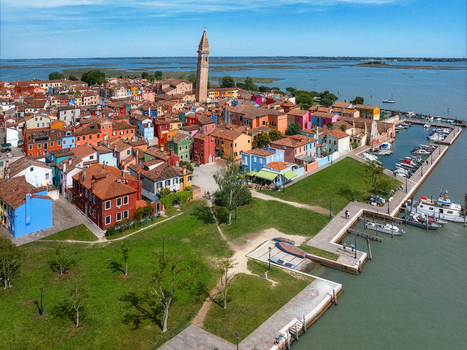 Aerial view of vibrantly colored houses clustered around the leaning bell tower of Burano a picturesque island with a bustling marina and serene waterways Venice Veneto Italy. Aerial view of vibrantly colored houses clustered around the leaning bell tower of Burano a picturesque island with a bustling marina and serene waterways Venice Veneto Italy.