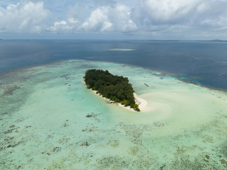 Aerial view of a lush green island embraced by shallow turquoise waters a serene escape under a vast sky Karimunjawa Central Java Indonesia.