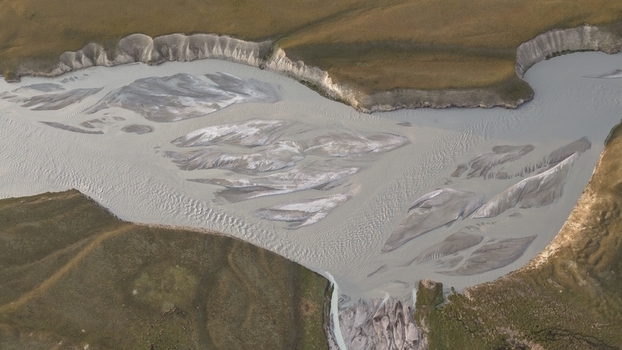 Aerial view of the braided Enilchek River with silt laden glacial water flowing through the rugged landscape of the Tian Shan mountains in Enilchek Issyk Kul Region Kyrgyzstan. Aerial view of the braided Enilchek River with silt laden glacial water flowing through the rugged landscape of the Tian Shan mountains in Enilchek Issyk Kul Region Kyrgyzstan.
