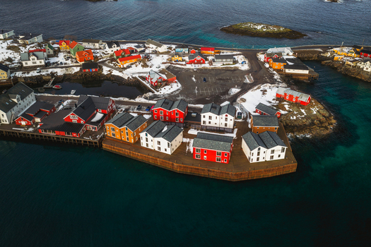 Aerial view of colorful buildings contrasting against the snow dusted landscape and the deep blue sea Henningsv&aelig;r Nordland Norway.