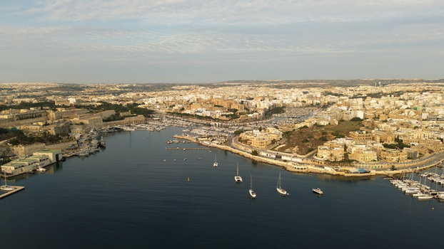 Aerial view of the historic harbor in Valletta with numerous sailboats and yachts moored in the calm blue water surrounded by traditional limestone architecture and fortifications in Malta. Aerial view of the historic harbor in Valletta with numerous sailboats and yachts moored in the calm blue water surrounded by traditional limestone architecture and fortifications in Malta.