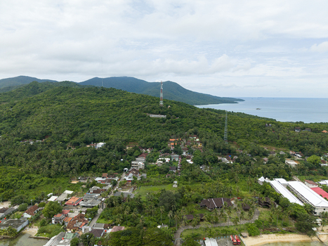 Aerial view of lush green hills cascading into the turquoise waters of the sea punctuated by a small coastal village Karimunjawa Central Java Indonesia. Aerial view of lush green hills cascading into the turquoise waters of the sea punctuated by a small coastal village Karimunjawa Central Java Indonesia.