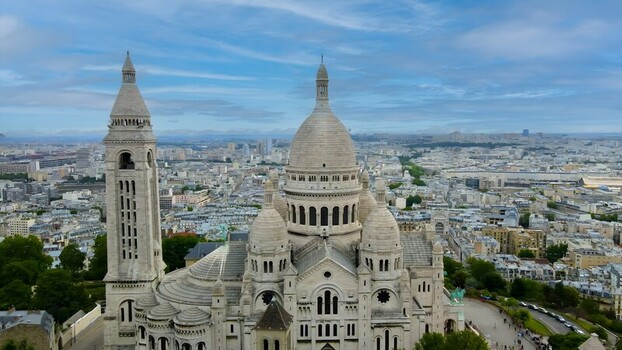 Aerial view of the Sacre Coeur Basilica with its white stone domes and bell tower overlooking the sprawling cityscape of Paris Ile de France France. Aerial view of the Sacre Coeur Basilica with its white stone domes and bell tower overlooking the sprawling cityscape of Paris Ile de France France.