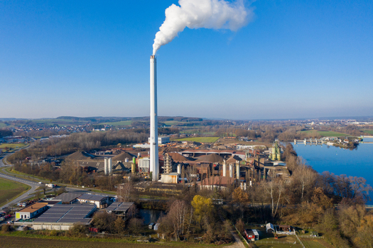Aerial view of the Liapor GmbH Co. KG industrial plant featuring a tall white chimney with smoke plumes near the river Hallerndorf Bayern Germany. Aerial view of the Liapor GmbH Co. KG industrial plant featuring a tall white chimney with smoke plumes near the river Hallerndorf Bayern Germany.