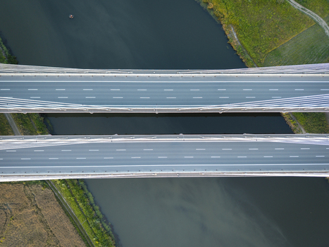 Aerial view of Most na S7 cable stayed bridge spanning over a river with green fields and vegetation in the surrounding landscape Krakow Wojewodztwo malopolskie Poland. Aerial view of Most na S7 cable stayed bridge spanning over a river with green fields and vegetation in the surrounding landscape Krakow Wojewodztwo malopolskie Poland.