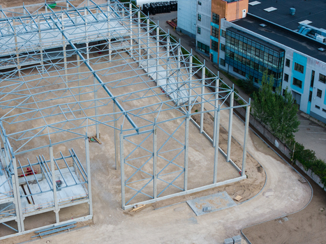 Aerial view of a steel frame construction site with concrete pillars and dirt ground next to a modern building in Riga Latvia. Aerial view of a steel frame construction site with concrete pillars and dirt ground next to a modern building in Riga Latvia.