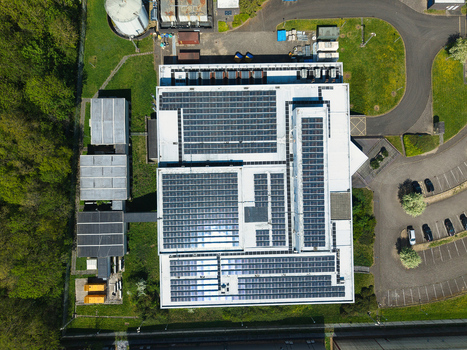 Aerial view of the solar panel arrays on the roof of a modern data centre surrounded by lush green trees and industrial infrastructure in Wellingborough England United Kingdom. Aerial view of the solar panel arrays on the roof of a modern data centre surrounded by lush green trees and industrial infrastructure in Wellingborough England United Kingdom.
