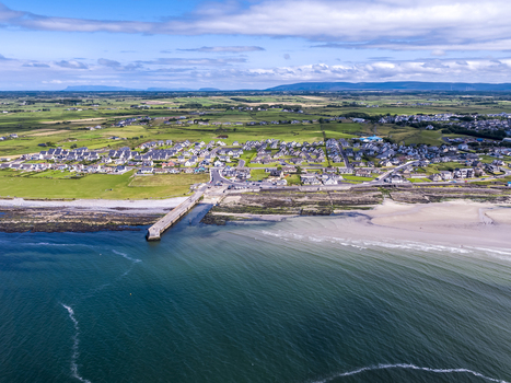 Aerial view of Enniscrone Pier extending into the Atlantic Ocean with the coastal town sandy beach and green fields of County Sligo Enniscrone County Sligo Ireland.