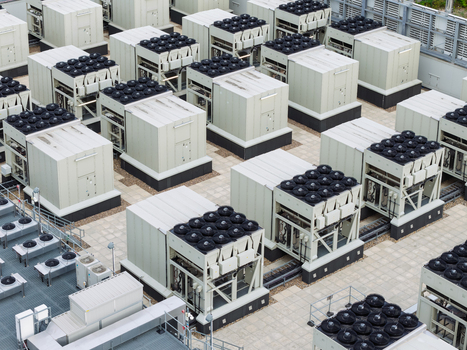 Aerial view of a data center rooftop featuring rows of industrial cooling units and ventilation fans on a paved surface in the United Kingdom.