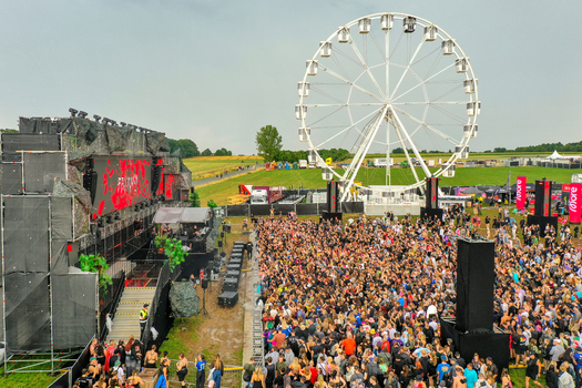 Herzogenaurach Germany 24 July 2025 Aerial view of the Open Beatz Festival featuring a large main stage a white Ferris wheel and a dense crowd of people in an open field.