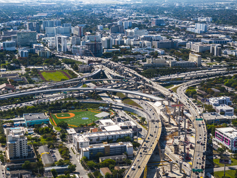 Aerial view of the vibrant cityscape where concrete ribbons of highways intertwine leading to downtown skyscrapers in the distance Miami Florida USA. Aerial view of the vibrant cityscape where concrete ribbons of highways intertwine leading to downtown skyscrapers in the distance Miami Florida USA.