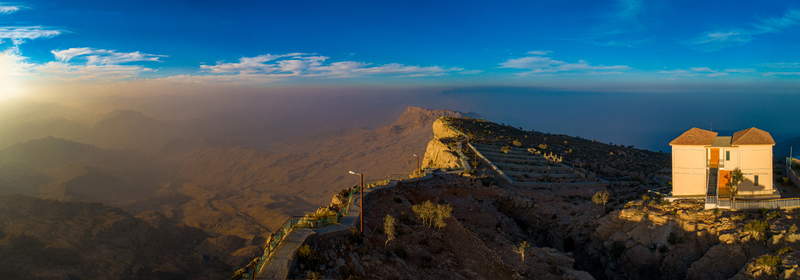 View of Gorakh Hill Station at sunset featuring a building perched on a rocky mountain ridge overlooking the vast hazy landscape of Gorakh Hill Sindh Pakistan.