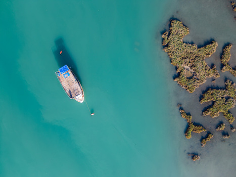 Aerial view of a wooden boat on the turquoise waters of the Kanali i Vivarit Vrine Vlore County Albania. Aerial view of a wooden boat on the turquoise waters of the Kanali i Vivarit Vrine Vlore County Albania.