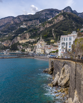 Aerial view of the rugged coastline meeting the turquoise sea near the historic town cradled by majestic mountains Amalfi Campania Italy. Aerial view of the rugged coastline meeting the turquoise sea near the historic town cradled by majestic mountains Amalfi Campania Italy.
