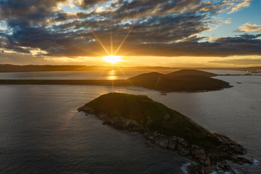 Aerial view of the Torndirrup coastline at sunset featuring rugged islands surrounded by the Southern Ocean under a dramatic golden sky in Albany Western Australia Australia. Aerial view of the Torndirrup coastline at sunset featuring rugged islands surrounded by the Southern Ocean under a dramatic golden sky in Albany Western Australia Australia.