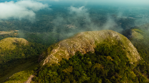 Aerial view of Mt. Gemi covered in lush green forest and rocky terrain with clouds drifting over the landscape in Amedzofe Volta Region Ghana. Aerial view of Mt. Gemi covered in lush green forest and rocky terrain with clouds drifting over the landscape in Amedzofe Volta Region Ghana.