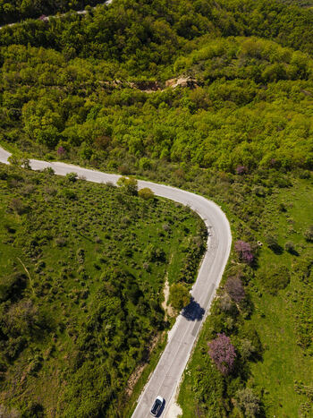 Aerial view of a winding road cutting through the lush green hills and dense forest near Muzina Qarku i Vlores Albania. Aerial view of a winding road cutting through the lush green hills and dense forest near Muzina Qarku i Vlores Albania.