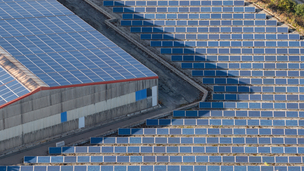Aerial view of a large industrial building with solar panels on its roof surrounded by extensive rows of ground mounted solar panels in Ludwigshafen Rhineland Palatinate Germany. Aerial view of a large industrial building with solar panels on its roof surrounded by extensive rows of ground mounted solar panels in Ludwigshafen Rhineland Palatinate Germany.