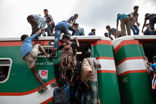 Dhaka Bangladesh 14 June 2018 View of crowds of passengers climbing onto the roof and hanging from the doors of a green and red train at Airport Railway Station. Dhaka Bangladesh 14 June 2018 View of crowds of passengers climbing onto the roof and hanging from the doors of a green and red train at Airport Railway Station.
