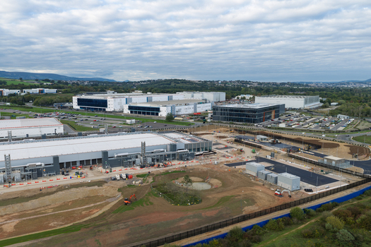 Aerial view of a large data center construction site with industrial buildings heavy machinery and excavation work in the United Kingdom.