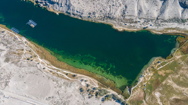 Aerial view of Blind Lake Sarfaranga Shigar with its deep green waters surrounded by arid desert landscape and sandy terrain in Skardu Gilgit Pakistan.