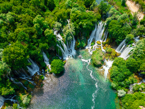Aerial view of the cascading Kravica Waterfall surrounded by lush green forests and turquoise waters in Zvirici Federation of Bosnia Bosnia and Herzegovina. Aerial view of the cascading Kravica Waterfall surrounded by lush green forests and turquoise waters in Zvirici Federation of Bosnia Bosnia and Herzegovina.
