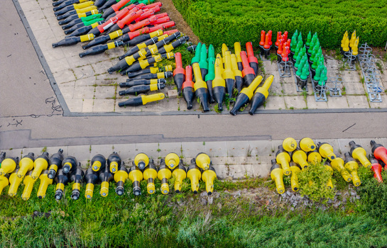 Aerial view of Rijkswaterstaat Harderhaven showing rows of colorful navigation buoys stored on a paved surface near green grass in Zeewolde Flevoland Netherlands.