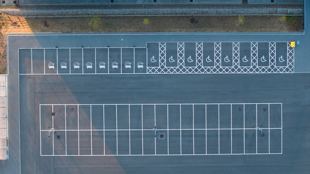 Aerial view of a parking lot featuring designated electric vehicle charging spaces and marked disabled parking bays in Wellingborough England United Kingdom. Aerial view of a parking lot featuring designated electric vehicle charging spaces and marked disabled parking bays in Wellingborough England United Kingdom.