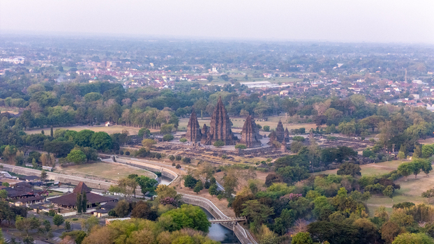 Aerial view of Prambanan Temple surrounded by lush greenery ancient stone structures and a winding river in Kecamatan Prambanan Daerah Istimewa Yogya Indonesia.