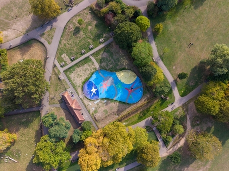 Aerial view of the colorful splash pad in Clissold Park surrounded by lush trees and winding pathways in Stoke Newington London England United Kingdom.
