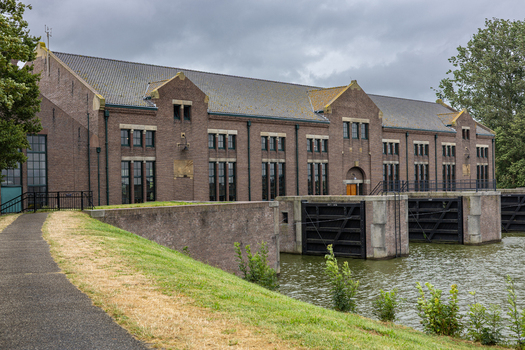View of the historic Wouda pumping station with its brick facade and sluice gates under a cloudy sky in Lemmer Friesland Netherlands.