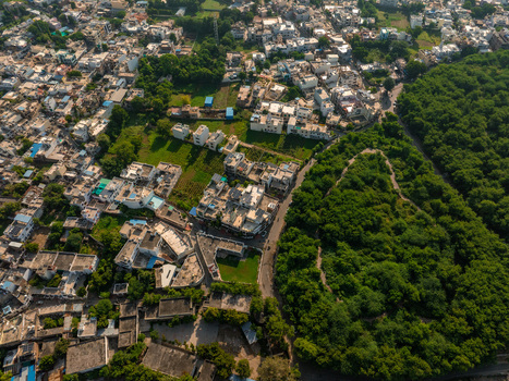 Aerial view of the residential rooftops urban streets and lush green forest bordering the city of Udaipur Rajasthan India.