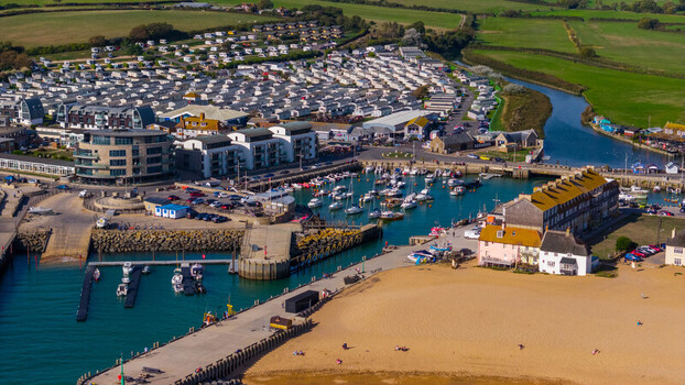 Aerial view of the harbour and marina at West Bay with boats docked a sandy beach and surrounding coastal buildings in West Bay England United Kingdom. Aerial view of the harbour and marina at West Bay with boats docked a sandy beach and surrounding coastal buildings in West Bay England United Kingdom.