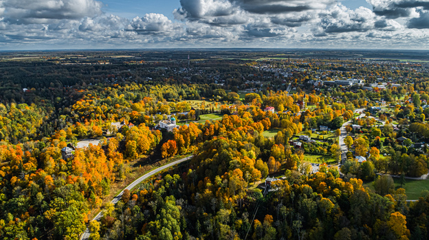 Aerial view of Sigulda town surrounded by vibrant autumn forests winding roads and historic buildings under a dramatic cloudy sky in Sigulda Sigulda Municipality Latvia. Aerial view of Sigulda town surrounded by vibrant autumn forests winding roads and historic buildings under a dramatic cloudy sky in Sigulda Sigulda Municipality Latvia.