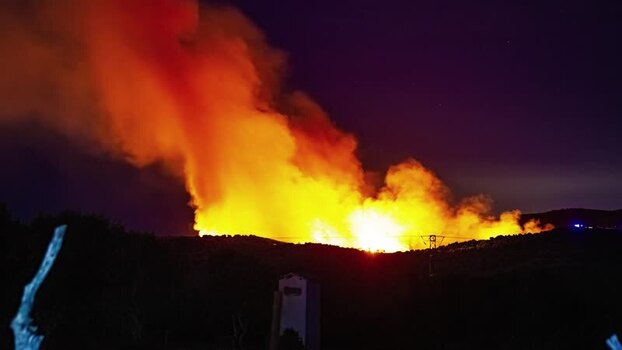 View of wildfire burning on a hillside at night in Spain.