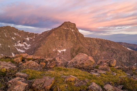 Aerial view of Mount of the Holy Cross in the Sawatch Range of the Rocky Mountains featuring rugged alpine terrain under a pink sunset sky in Vail Colorado United States. Aerial view of Mount of the Holy Cross in the Sawatch Range of the Rocky Mountains featuring rugged alpine terrain under a pink sunset sky in Vail Colorado United States.