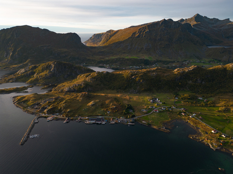 Aerial view of Tangstad village nestled between rugged mountains and the fjord with a small harbor and green fields in Leknes Nordland Norway. Aerial view of Tangstad village nestled between rugged mountains and the fjord with a small harbor and green fields in Leknes Nordland Norway.