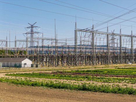 Aerial view of the Amprion Umspannwerk substation featuring complex electrical infrastructure and high voltage power lines set against agricultural fields in Pfungstadt Hessen Germany.