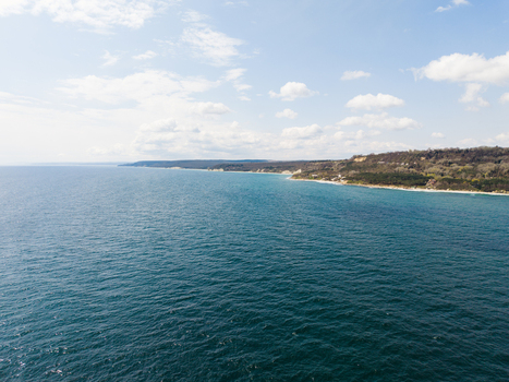 Aerial view of Fichoza Beach Veteran with turquoise sea forested cliffs and a clear blue sky with scattered clouds Varna Varna Bulgaria. Aerial view of Fichoza Beach Veteran with turquoise sea forested cliffs and a clear blue sky with scattered clouds Varna Varna Bulgaria.