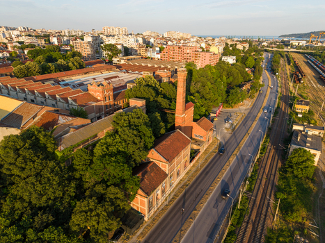 Aerial view of the historic Varna Thermal Power Plant with its iconic tall brick chimney surrounded by lush trees and adjacent to a railway line and urban cityscape Varna Varna Bulgaria. Aerial view of the historic Varna Thermal Power Plant with its iconic tall brick chimney surrounded by lush trees and adjacent to a railway line and urban cityscape Varna Varna Bulgaria.