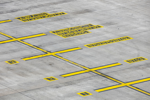 View of yellow aircraft parking position markings and aircraft model codes on the concrete tarmac at Berlin Brandenburg Airport BER Berlin Brandenburg Germany.