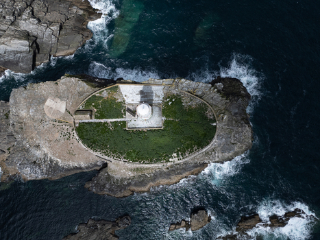 Aerial view of Godrevy Lighthouse situated on a rocky island surrounded by deep blue sea and crashing white waves at Gwithian England United Kingdom. Aerial view of Godrevy Lighthouse situated on a rocky island surrounded by deep blue sea and crashing white waves at Gwithian England United Kingdom.