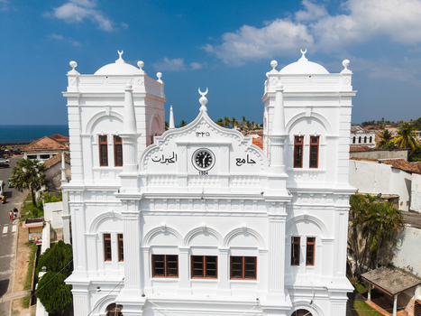 Aerial view of the white Meeran Jumma Mosque with its distinctive clock and crescent symbols under a blue sky in Galle Southern Province Sri Lanka. Aerial view of the white Meeran Jumma Mosque with its distinctive clock and crescent symbols under a blue sky in Galle Southern Province Sri Lanka.