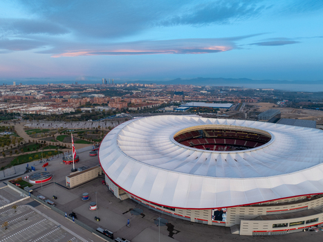 Aerial view of Riyadh Air Metropolitano Stadium with its distinctive white roof and surrounding parking areas set against the urban skyline of Madrid Comunidad de Madrid Spain.