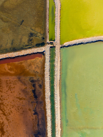 Aerial view of colorful salt pans with distinct mineral rich water basins separated by narrow dirt paths in Andalusia Spain. Aerial view of colorful salt pans with distinct mineral rich water basins separated by narrow dirt paths in Andalusia Spain.