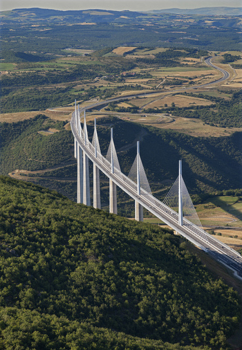 Aerial view of the Viaduc de Millau piercing the sky with its sleek white pillars a modern marvel amidst the rolling green hills Millau Occitanie France. Aerial view of the Viaduc de Millau piercing the sky with its sleek white pillars a modern marvel amidst the rolling green hills Millau Occitanie France.