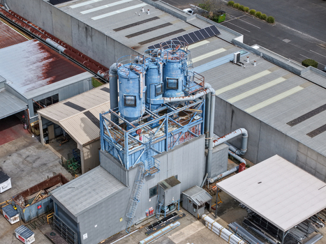 Melbourne VIC Australia 25 September 2026 Aerial view of an industrial facility featuring blue dust collection silos metal piping and factory rooftops in an urban setting.