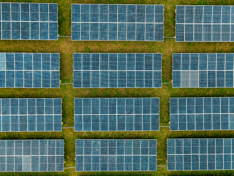 Aerial view of a solar farm with rows of photovoltaic panels installed on green grass in Ogun State Nigeria.