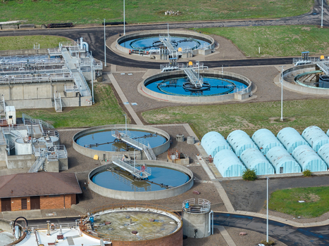 Aerial view of the wastewater treatment plant featuring circular clarifiers with blue water industrial infrastructure and concrete tanks in Woodburn Oregon United States. Aerial view of the wastewater treatment plant featuring circular clarifiers with blue water industrial infrastructure and concrete tanks in Woodburn Oregon United States.