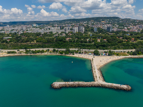 Aerial view of Alley First promenade and beach with a stone breakwater extending into the Black Sea featuring the Varna city skyline in the background Varna Varna Bulgaria. Aerial view of Alley First promenade and beach with a stone breakwater extending into the Black Sea featuring the Varna city skyline in the background Varna Varna Bulgaria.
